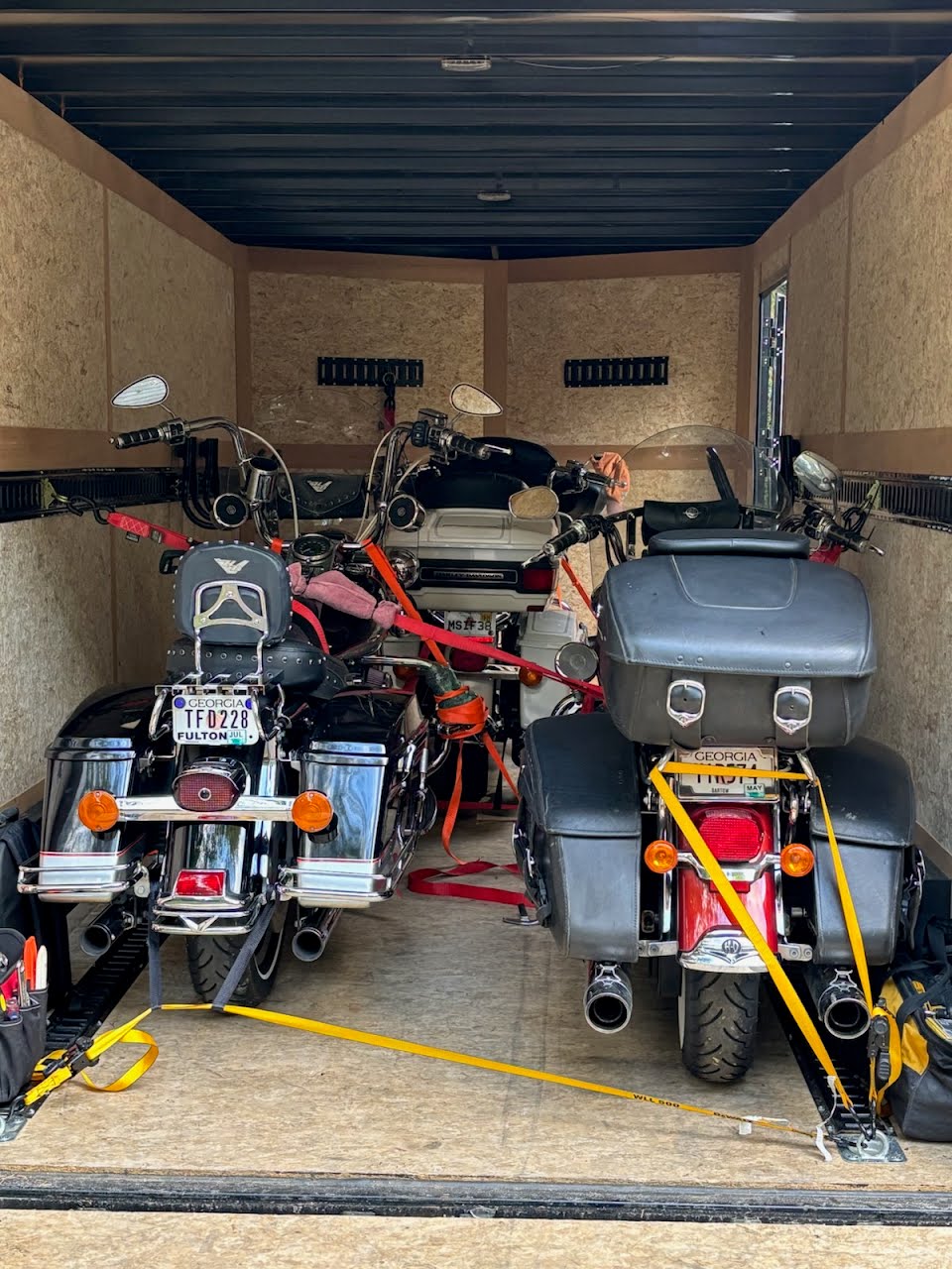 Enclosed trailer interior loaded with multiple motorcycles secured with straps