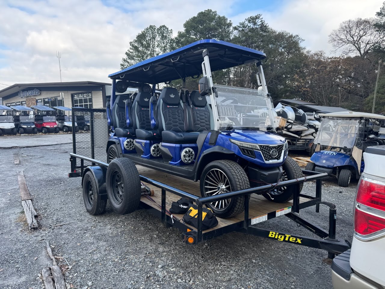 Blue 6-seater golf cart on a Big Tex trailer at a golf cart dealership