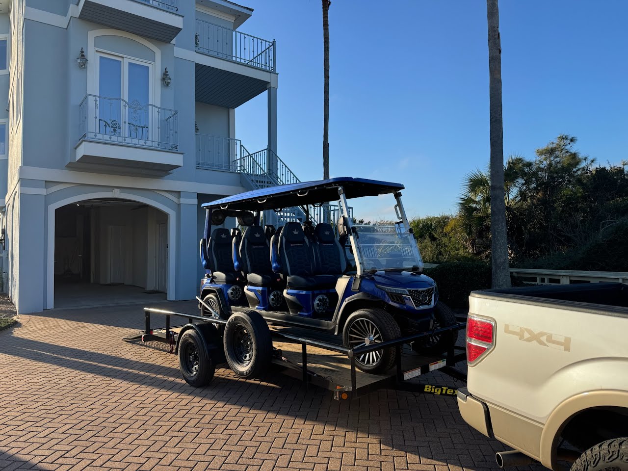 Blue 6-seater luxury golf cart on a Big Tex trailer at a beach house