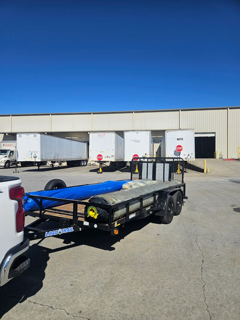 Load Trail utility trailer with tarped materials at a loading dock