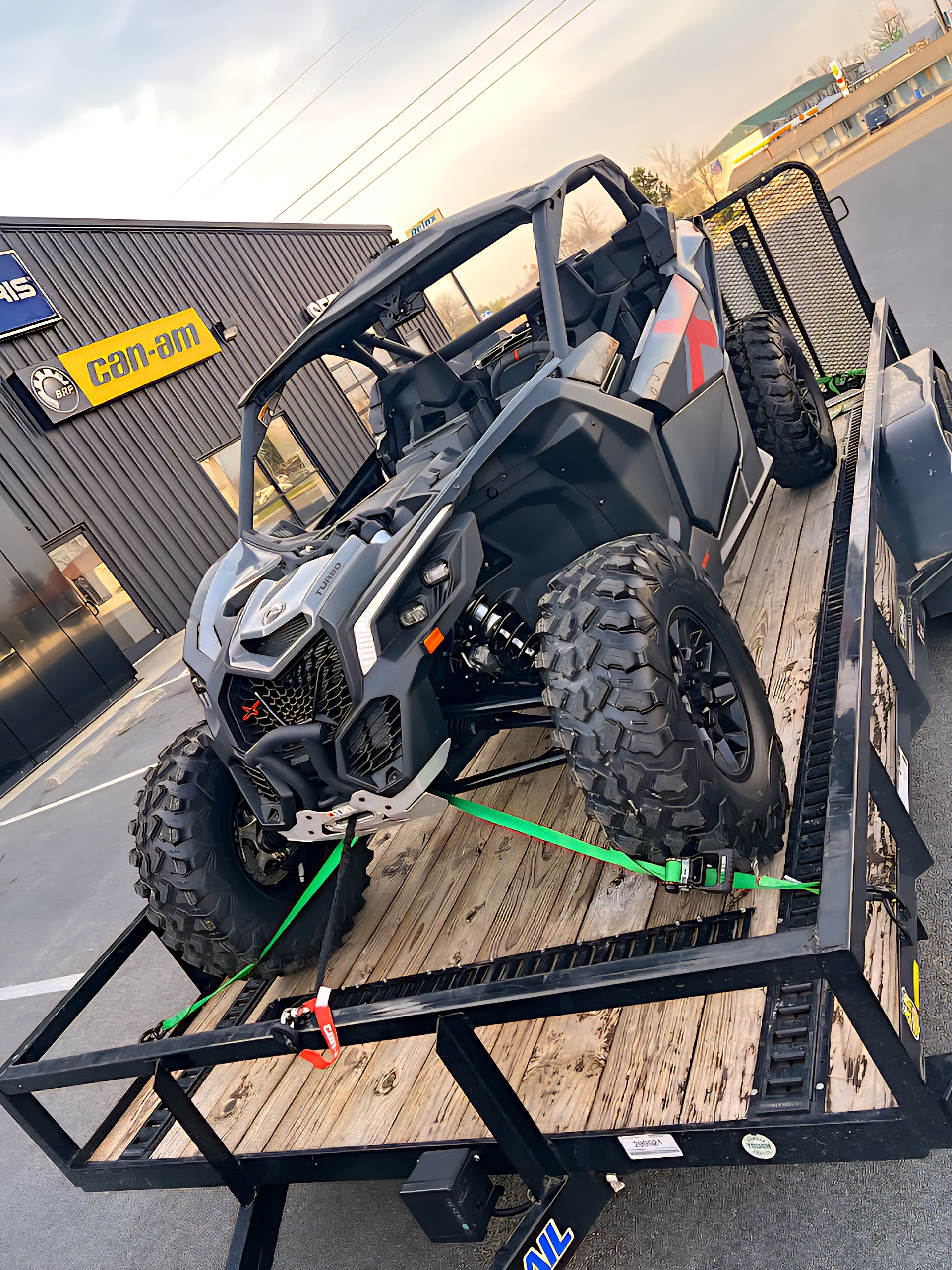 Gray Can-Am Maverick Turbo UTV on a utility trailer at a dealership