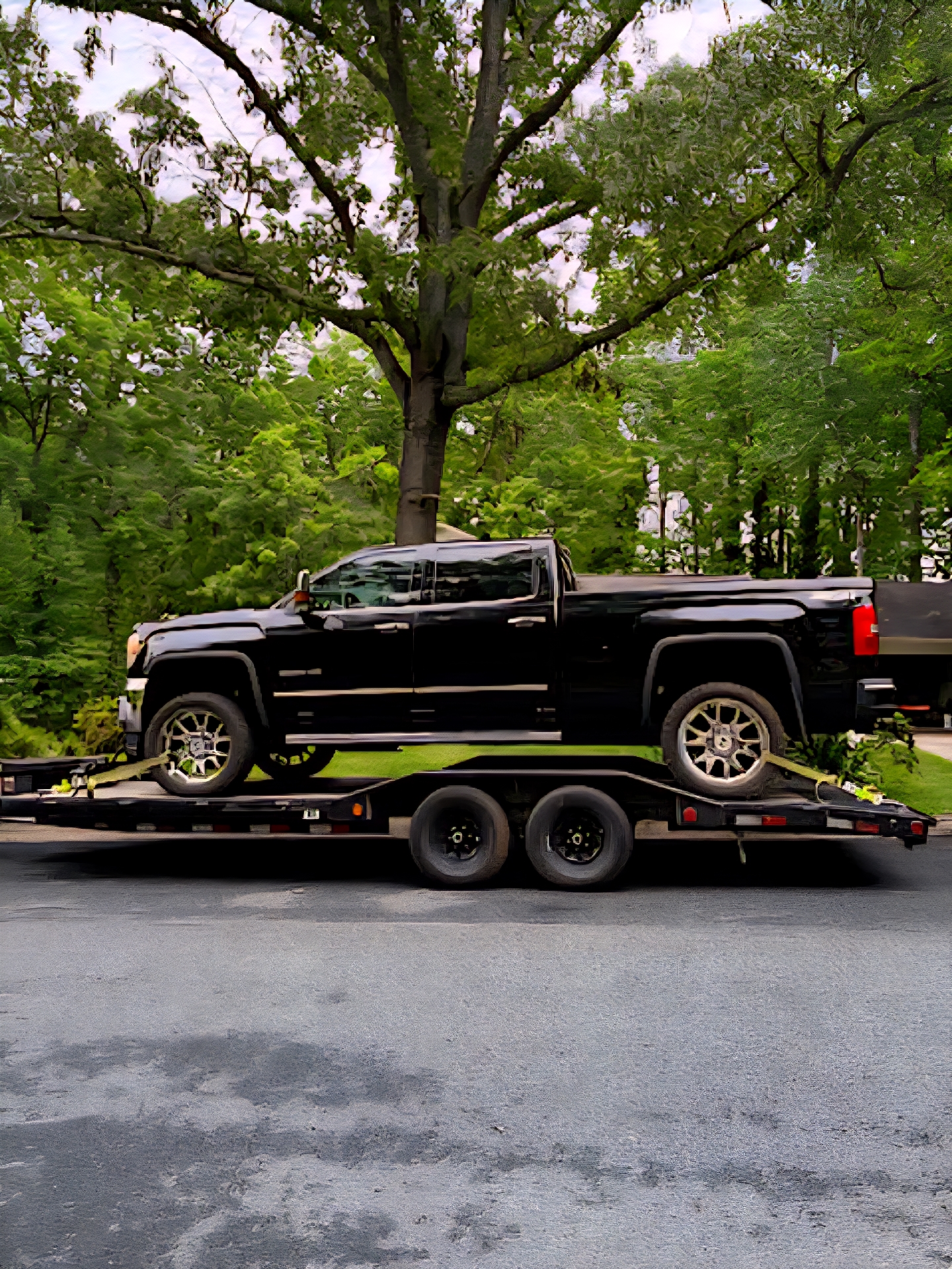 Flatbed trailer carrying a black GMC pickup truck