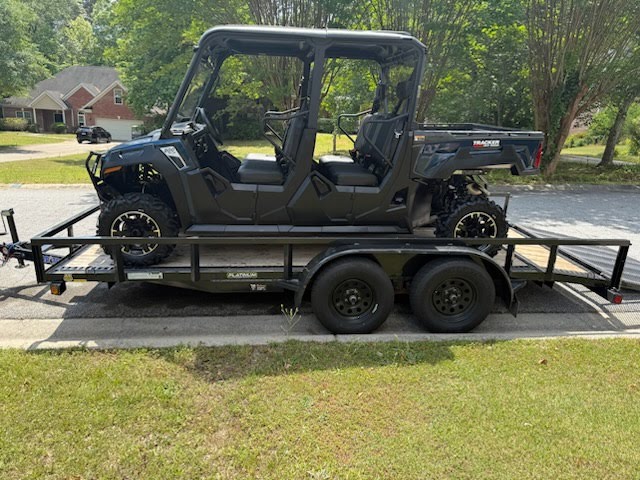 Utility trailer carrying a black Tracker side-by-side UTV