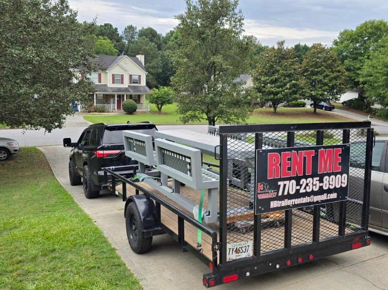 Utility trailer loaded with deck and construction materials, towed by a black SUV