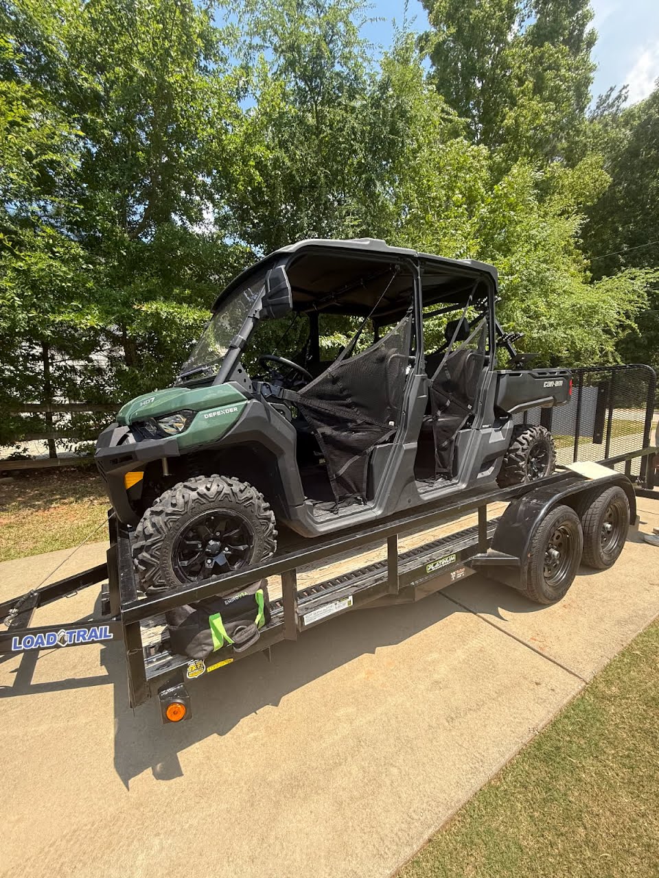 Utility trailer carrying a green Can-Am Defender side-by-side UTV