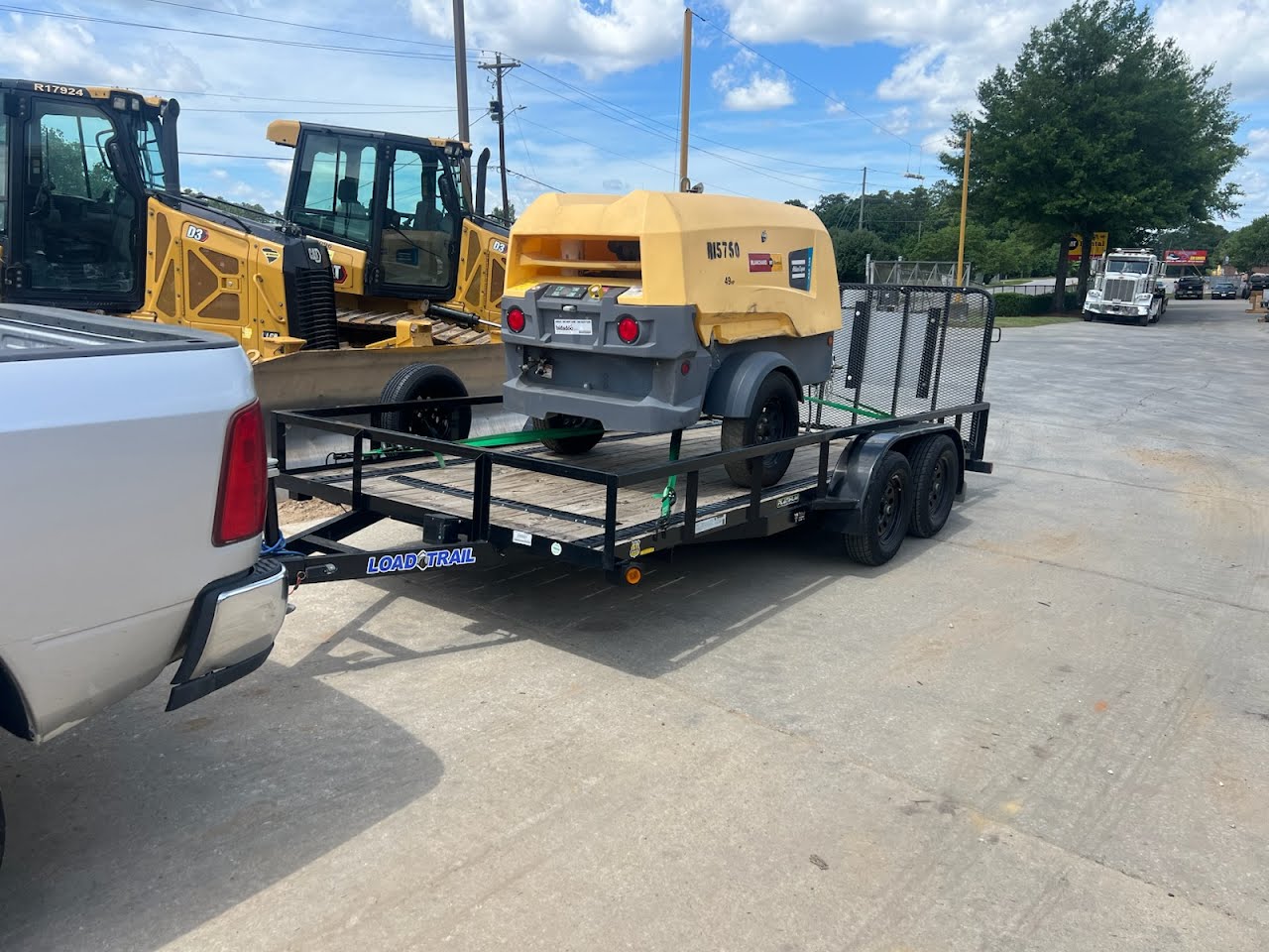 Load Trail utility trailer hauling a yellow air compressor in an equipment yard