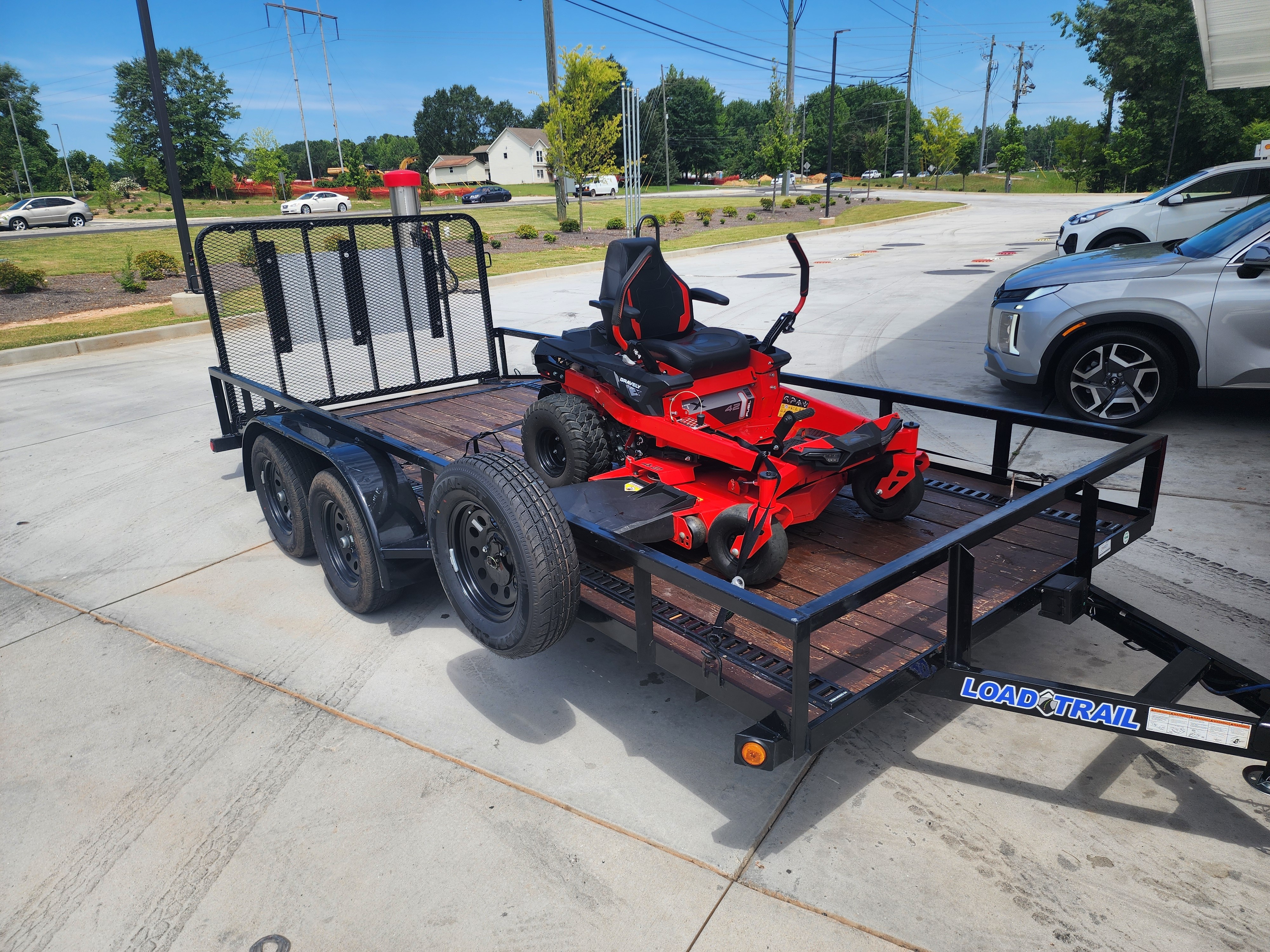 Utility trailer loaded with a red zero-turn lawn mower