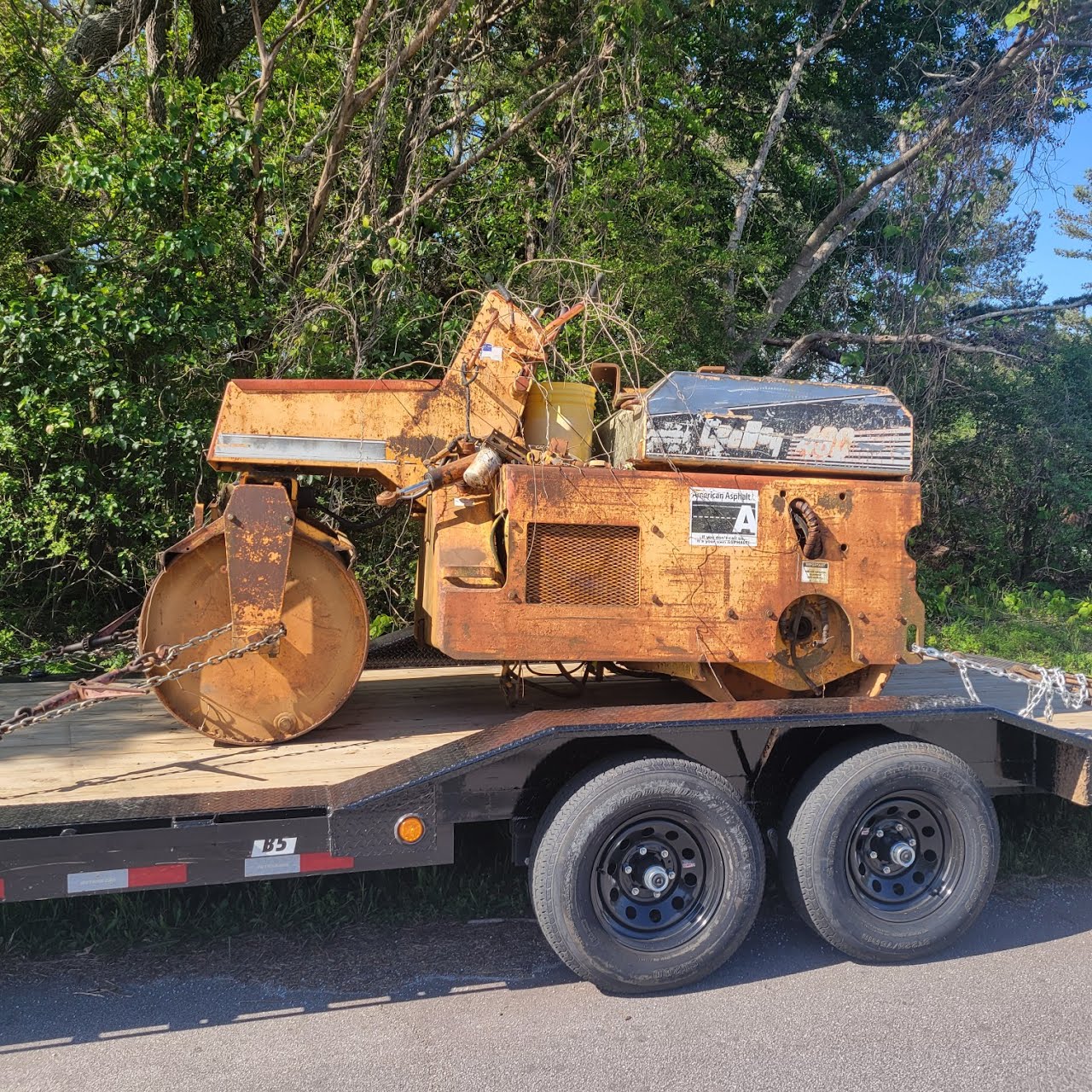 Utility trailer loaded with a rusty road roller
