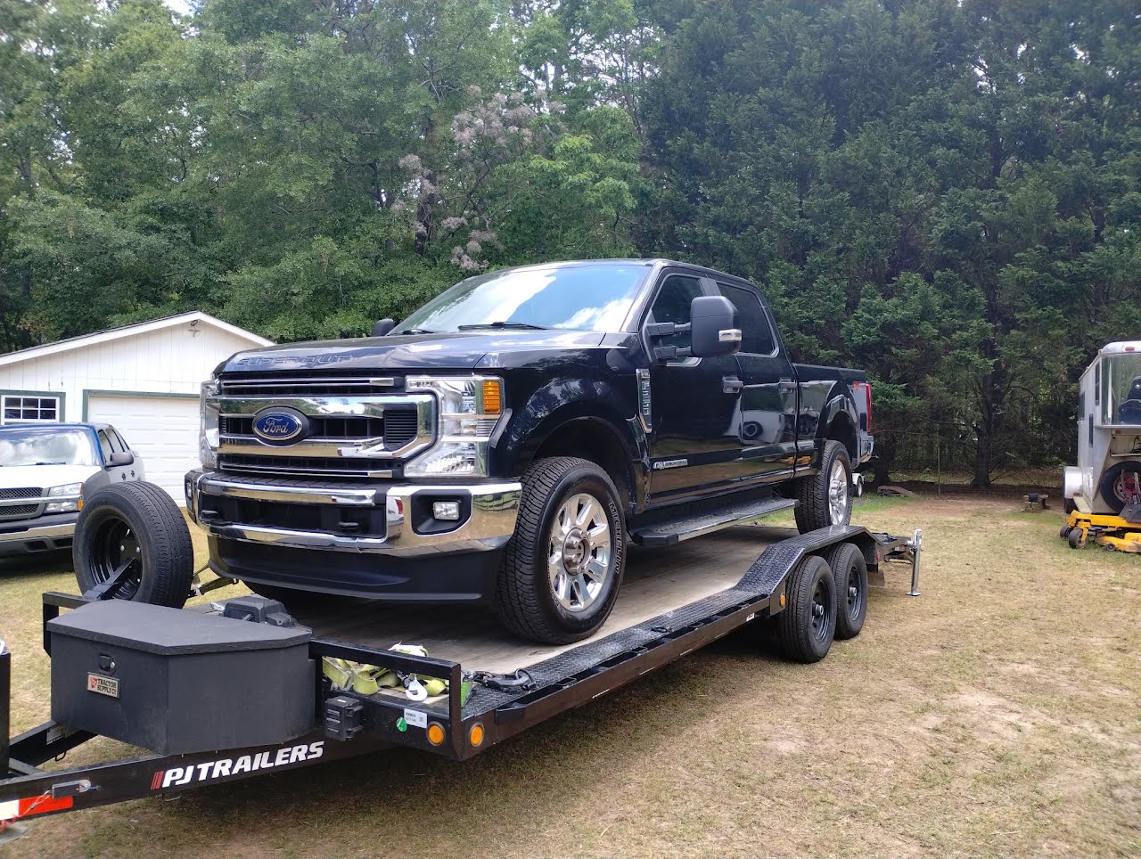 Utility trailer loaded with a black Ford F-series pickup truck