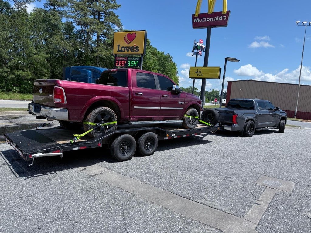 Utility trailer loaded with a red Ram pickup truck
