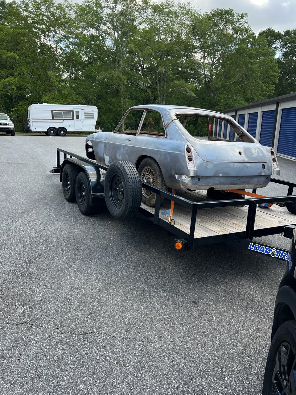 Utility trailer loaded with a grey car body