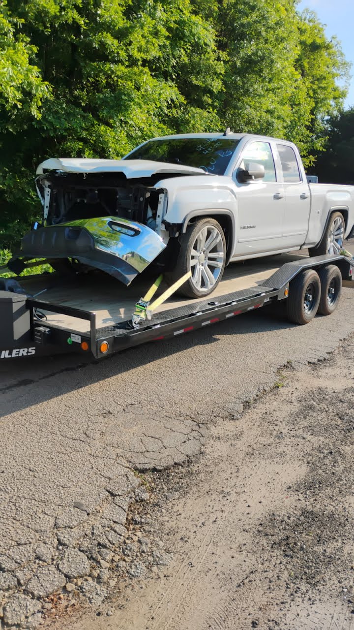 Utility trailer loaded with a damaged white pickup truck