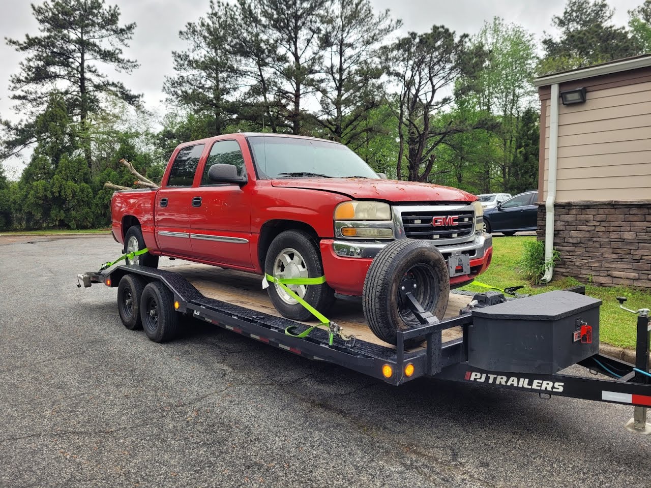 Utility trailer loaded with a red GMC pickup truck