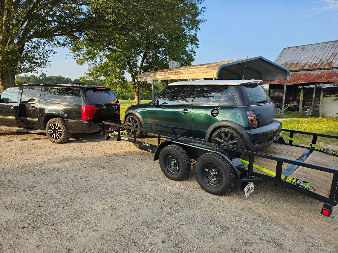 Utility trailer loaded with a green Mini Cooper