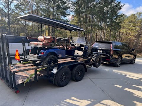 Utility trailer loaded with a blue golf cart