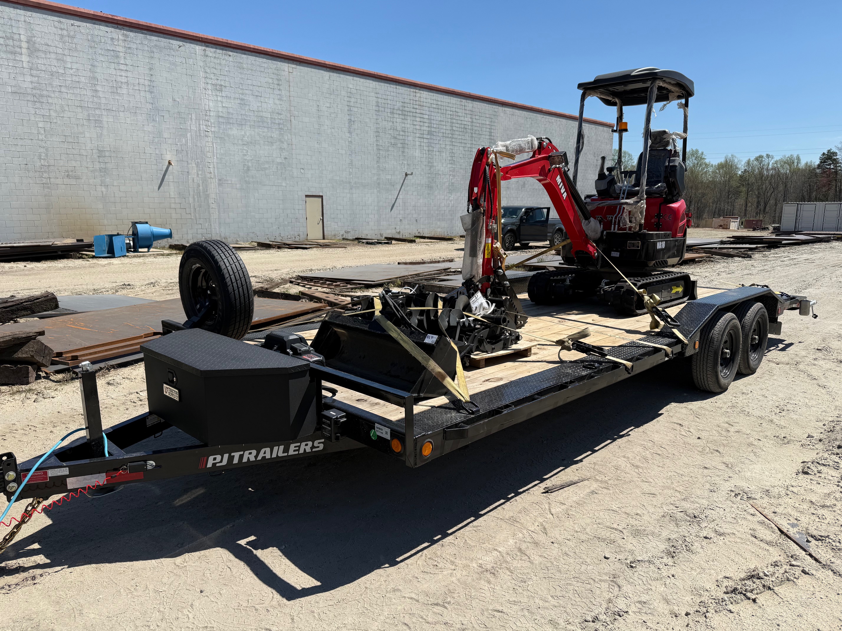 Utility trailer loaded with a red mini excavator