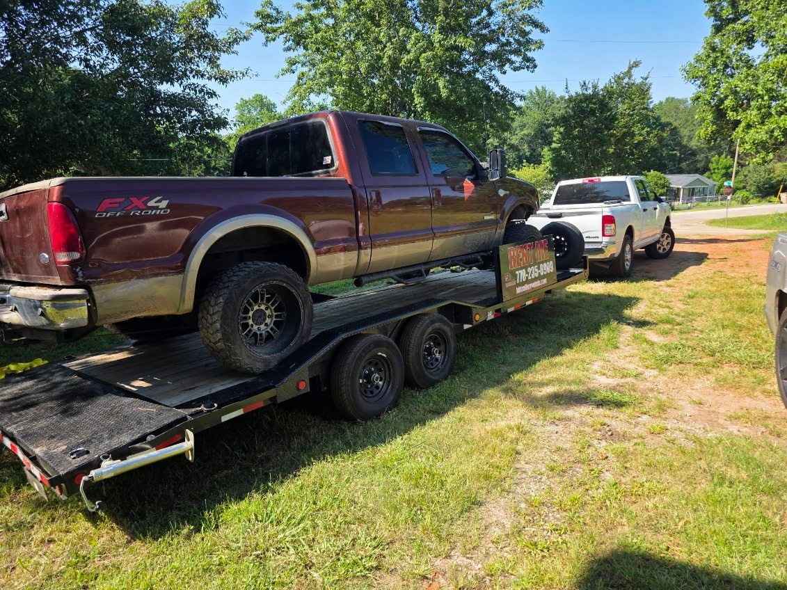 Flatbed trailer loaded with a brown Ford F-250 pickup truck