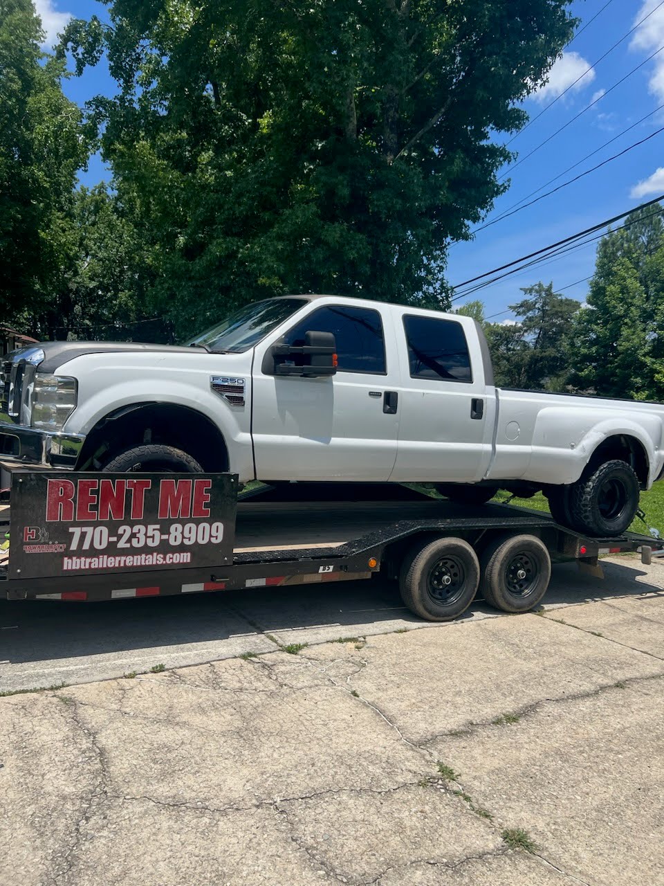 Utility trailer loaded with a white Ford F-350 dually