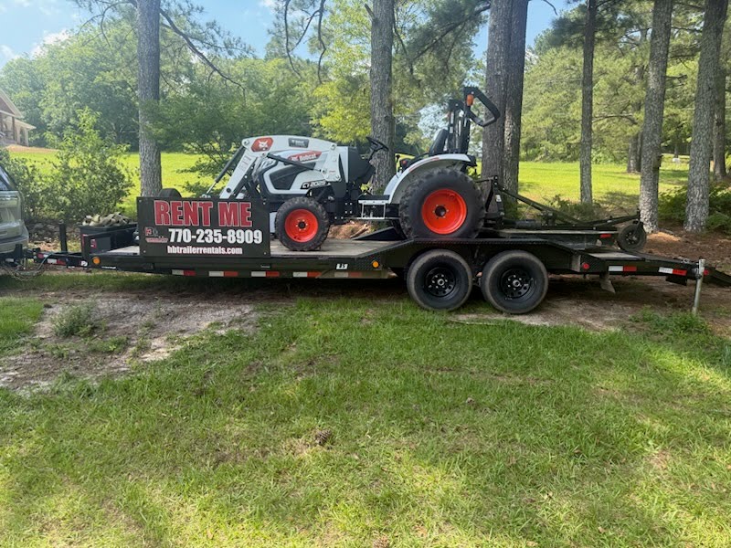 Utility trailer loaded with a white Bobcat tractor