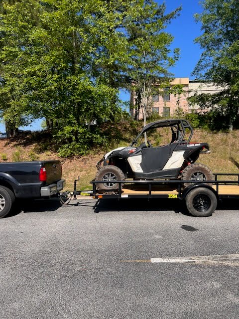 Utility trailer loaded with a white and black side-by-side
