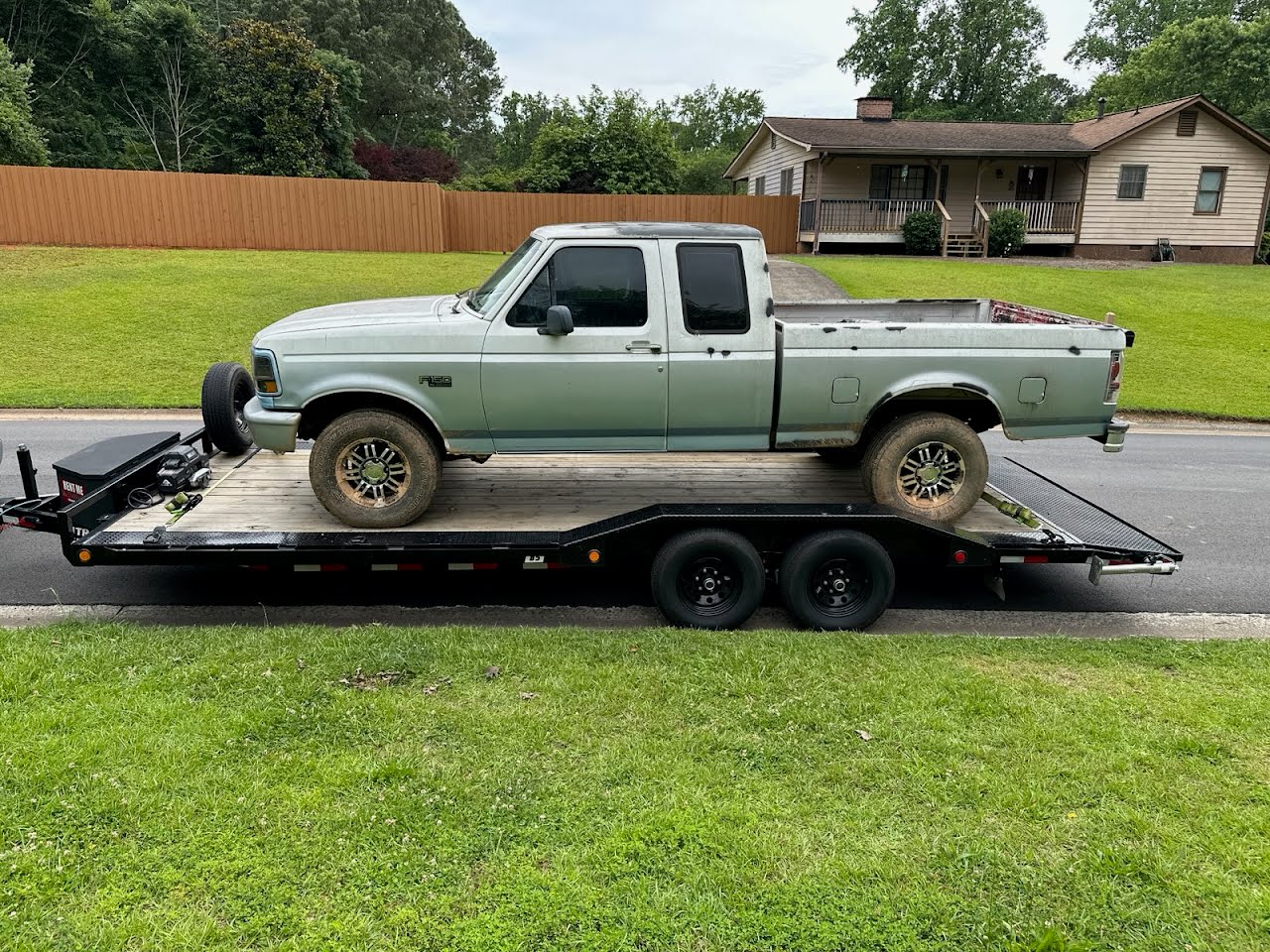 Utility trailer loaded with an older model pickup truck