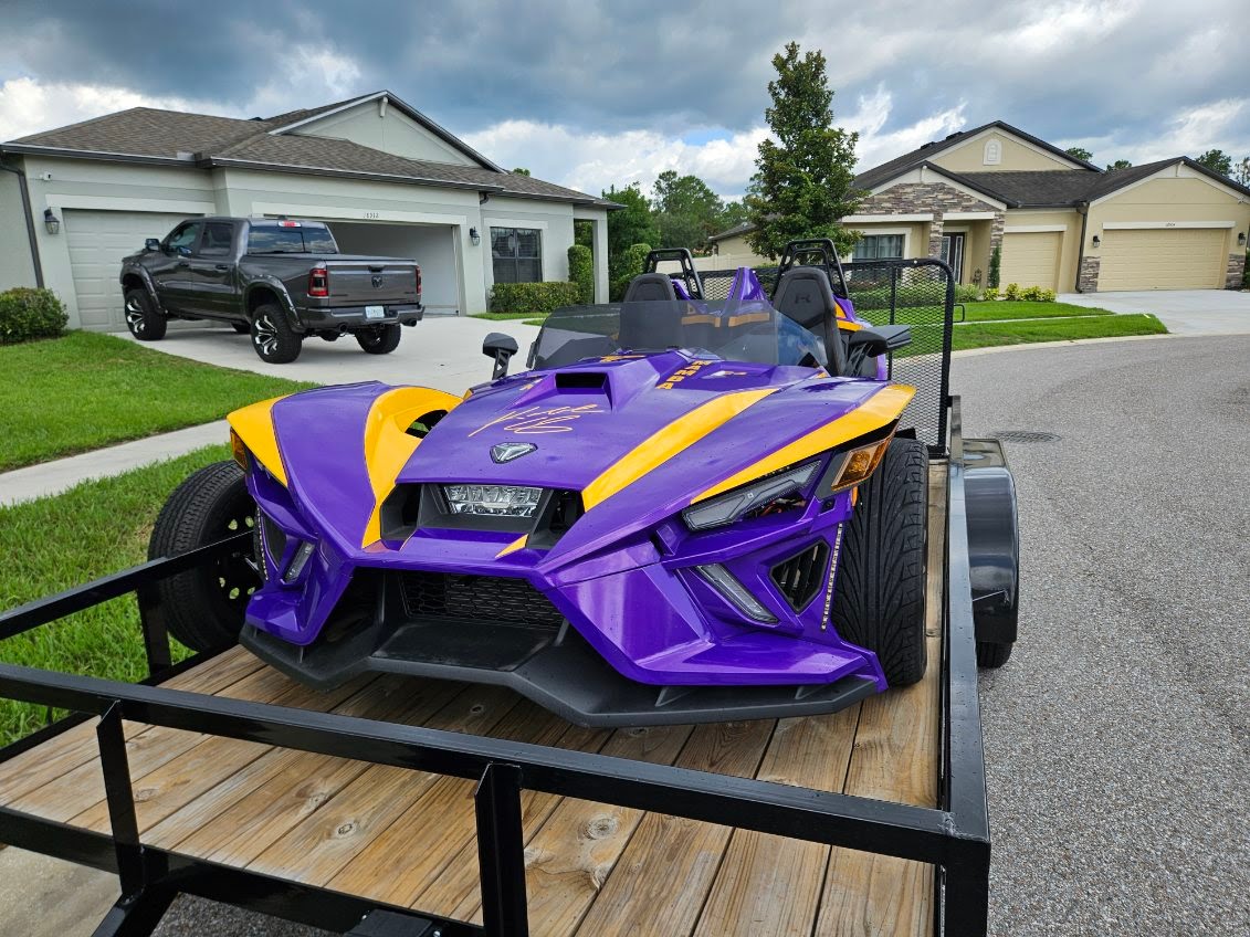Utility trailer loaded with purple and yellow Polaris Slingshot