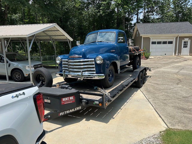 Utility trailer loaded with a blue vintage pickup truck